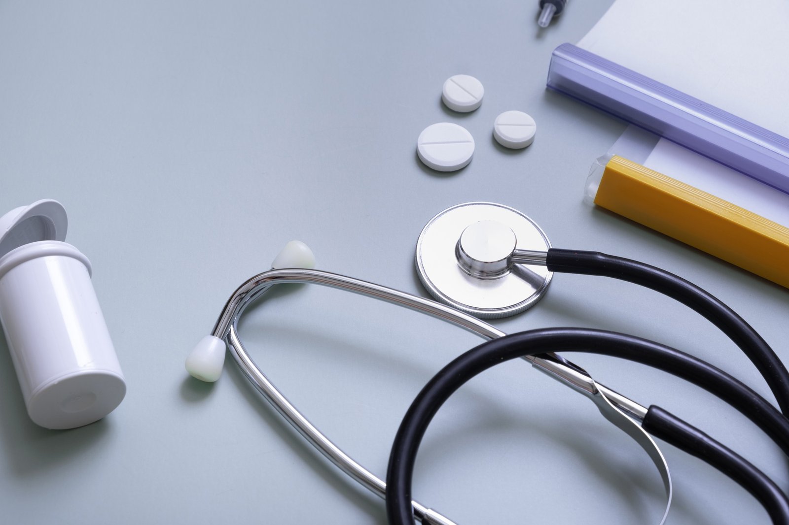 Stethoscope, pills and papers on colored background. Abstract medical background